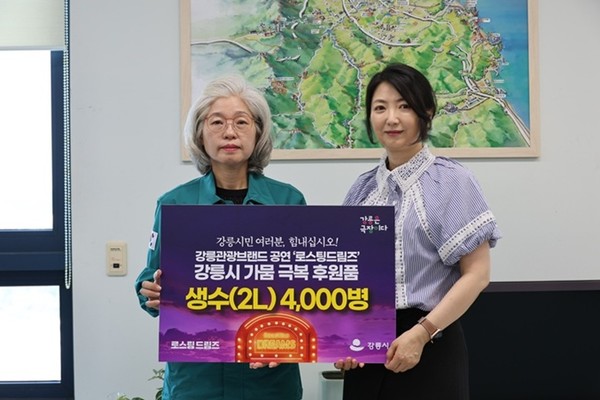 사진 설명/‘로스팅 드림즈’ 최미경 총괄프로듀서(오른쪽)는 강릉시청을 방문해 심상복 강릉시 문화관광해양국장에게 강릉가뭄극복 동참을 위한 생수(2L) 4000병을 전달했다.